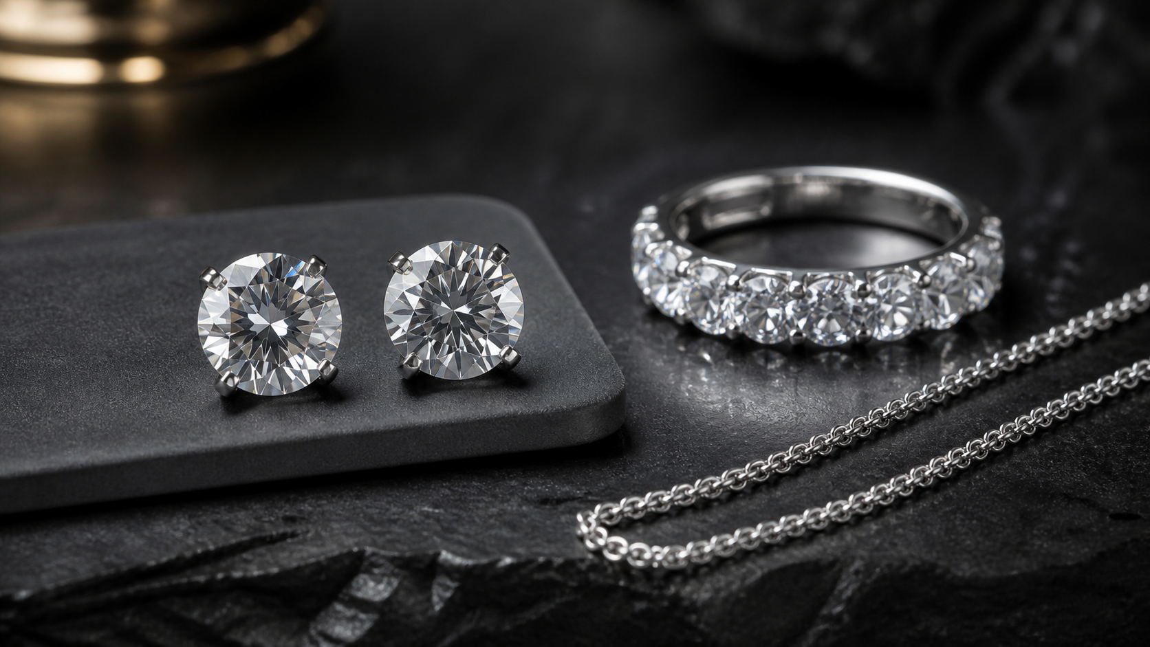 Clear stones with an iced ring and chain on a dark studio surface for a jewelry material comparison